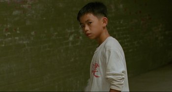 Movie still from “A Brighter Summer Day” (1991), directed by Edward Yang – A young boy standing in front of a brick wall; Medium shot, Over the shoulder angle