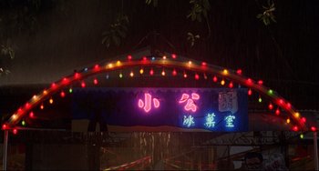Movie still from “A Brighter Summer Day” (1991), directed by Edward Yang – A neon sign is lit up at night in the rain; Extreme Wide shot, Low angle