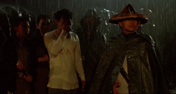 Movie still from “A Brighter Summer Day” (1991), directed by Edward Yang – A group of people standing in the rain with umbrellas; Medium shot, Over the shoulder angle