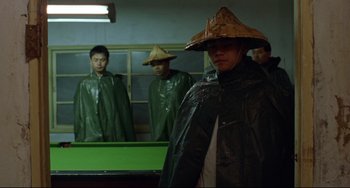 Movie still from “A Brighter Summer Day” (1991), directed by Edward Yang – A group of men in rain gear standing next to a pool table; Medium shot, High angle