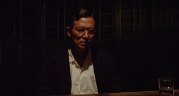 Movie still from “A Brighter Summer Day” (1991), directed by Edward Yang – A man with glasses sitting in front of a window; Medium shot, Low angle
