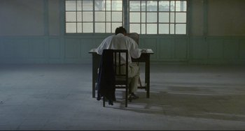 Movie still from “A Brighter Summer Day” (1991), directed by Edward Yang – Two people sitting at a table with their heads on the table; Wide shot, High angle