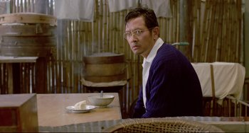 Movie still from “A Brighter Summer Day” (1991), directed by Edward Yang – A man sitting at a table with a bowl of rice; Medium shot, Over the shoulder angle