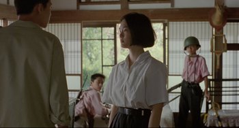 Movie still from “A Brighter Summer Day” (1991), directed by Edward Yang – A woman in a white shirt and a black skirt; Medium shot, Over the shoulder angle
