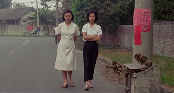 Movie still from “A Brighter Summer Day” (1991), directed by Edward Yang – Two women are walking down the street together; Wide shot, Low angle