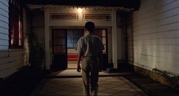 Movie still from “A Brighter Summer Day” (1991), directed by Edward Yang – A man walking in front of a building at night; Wide shot, Low angle