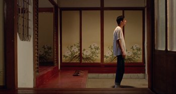 Movie still from “A Brighter Summer Day” (1991), directed by Edward Yang – A young man standing in front of an asian screen; Wide shot, Low angle
