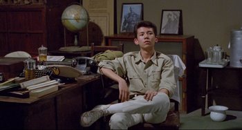 Movie still from “A Brighter Summer Day” (1991), directed by Edward Yang – A man sitting on a chair in a room; Medium shot, Low angle