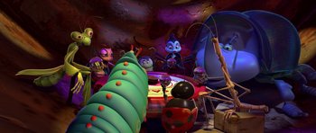 Movie still from “A Bug's Life” (1998), directed by John Lasseter – A group of people sitting at a table with a christmas tree in front of them; Extreme Wide shot, High angle