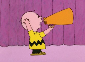 Movie still from “A Charlie Brown Christmas” (1965), directed by Bill Melendez – A charlie brown cartoon character is holding a megaphone to his mouth; Medium shot, Low angle