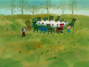 Movie still from “A Charlie Brown Thanksgiving” (1973), directed by Phil Roman – A group of people sitting around a table in a field; Extreme Wide shot, High angle