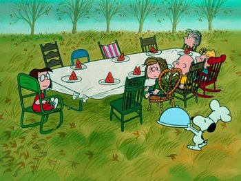 Movie still from “A Charlie Brown Thanksgiving” (1973), directed by Phil Roman – A group of people sitting around a table in the grass; Extreme Wide shot, High angle