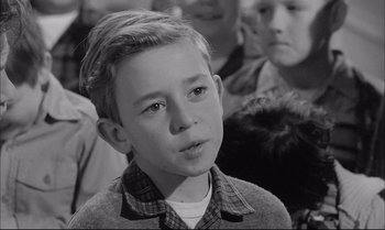 Movie still from “A Child Is Waiting” (1963), directed by John Cassavetes – A young boy in a plaid shirt is looking at the camera; Close Up shot, Over the shoulder angle