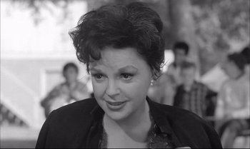 Movie still from “A Child Is Waiting” (1963), directed by John Cassavetes – A black - and - white photo of a woman in a crowd; Close Up shot, Over the shoulder angle