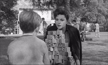 Movie still from “A Child Is Waiting” (1963), directed by John Cassavetes – A young boy is playing a game with blocks; Medium shot, Over the shoulder angle