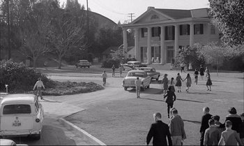 Movie still from “A Child Is Waiting” (1963), directed by John Cassavetes – A black and white photo of people walking on a street; Extreme Wide shot, High angle