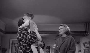 Movie still from “A Child Is Waiting” (1963), directed by John Cassavetes – A woman holding a young child in a room; Medium shot, Low angle