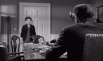 Movie still from “A Child Is Waiting” (1963), directed by John Cassavetes – A woman standing in front of a mirror in a room; Medium shot, Over the shoulder angle