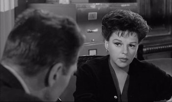 Movie still from “A Child Is Waiting” (1963), directed by John Cassavetes – A woman sitting in front of a man in front of an airplane; Close Up shot, Over the shoulder angle