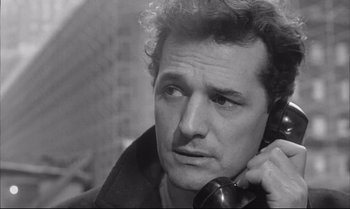 Movie still from “A Child Is Waiting” (1963), directed by John Cassavetes – A black and white photo of a man talking on a phone; Close Up shot, High angle