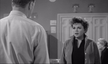 Movie still from “A Child Is Waiting” (1963), directed by John Cassavetes – An old photo of a man and a woman in a room; Medium shot, Over the shoulder angle