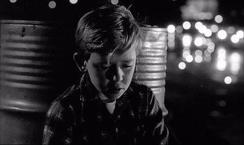 Movie still from “A Child Is Waiting” (1963), directed by John Cassavetes – A young boy sitting in front of a lamp post at night; Close Up shot, Low angle
