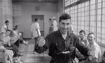 Movie still from “A Child Is Waiting” (1963), directed by John Cassavetes – A man holding a bag in front of a group of people; Medium shot, Low angle