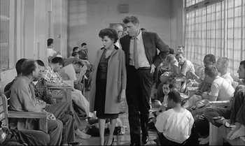 Movie still from “A Child Is Waiting” (1963), directed by John Cassavetes – A man and a woman walking in a room full of people; Wide shot, High angle