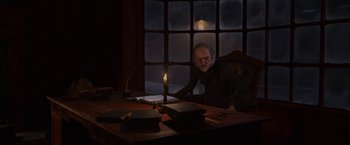 Movie still from “A Christmas Carol” (2009), directed by Robert Zemeckis – An old man sitting at a table with a candle in front of him; Medium shot, Over the shoulder angle