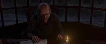 Movie still from “A Christmas Carol” (2009), directed by Robert Zemeckis – An old man sitting in front of a lit candle; Medium shot, Over the shoulder angle