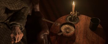 Movie still from “A Christmas Carol” (2009), directed by Robert Zemeckis – A candle lit next to a bowl and spoon on a wooden table; Extreme Close Up shot, High angle