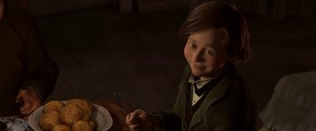 Movie still from “A Christmas Carol” (2009), directed by Robert Zemeckis – A boy sitting at a table with a plate of food in front of him; Medium shot, High angle