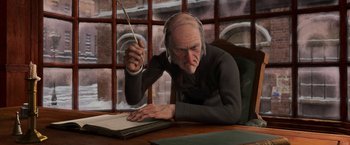 Movie still from “A Christmas Carol” (2009), directed by Robert Zemeckis – An old man wearing headphones is writing on a book; Medium shot, Over the shoulder angle