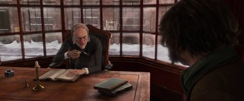 Movie still from “A Christmas Carol” (2009), directed by Robert Zemeckis – An old man sitting at a table with a book; Medium shot, Over the shoulder angle