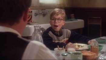 Movie still from “A Christmas Story” (1983), directed by Bob Clark – A young boy sitting at a table with a bottle of soda; Medium shot, Low angle
