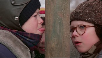 Movie still from “A Christmas Story” (1983), directed by Bob Clark – Two young children are looking at each other through a wooden pole; Close Up shot, Over the shoulder angle