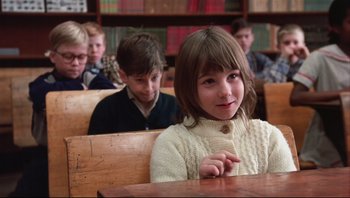 Movie still from “A Christmas Story” (1983), directed by Bob Clark – A little girl sitting at a table in front of a group of other kids; Close Up shot, Over the shoulder angle