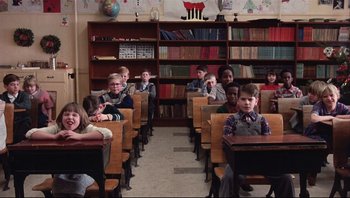 Movie still from “A Christmas Story” (1983), directed by Bob Clark – A group of children sitting at desks in front of a bookshelf; Wide shot, High angle