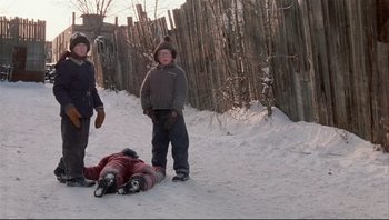 Movie still from “A Christmas Story” (1983), directed by Bob Clark – A group of people standing in the snow next to a person laying on the ground; Wide shot, Low angle