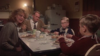 Movie still from “A Christmas Story” (1983), directed by Bob Clark – A group of people sitting at a table eating food; Medium shot, High angle