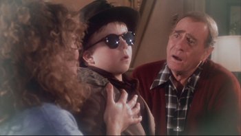 Movie still from “A Christmas Story” (1983), directed by Bob Clark – An older man and a young boy and a young woman; Medium shot, Over the shoulder angle