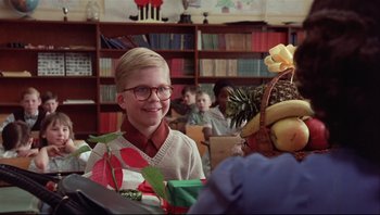 Movie still from “A Christmas Story” (1983), directed by Bob Clark – A young boy wearing glasses and a sweater is smiling; Medium shot, Over the shoulder angle