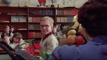 Movie still from “A Christmas Story” (1983), directed by Bob Clark – A boy wearing glasses sitting in front of a bookshelf; Medium shot, Low angle