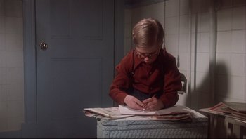 Movie still from “A Christmas Story” (1983), directed by Bob Clark – A young boy writing on a piece of paper; Medium shot, High angle