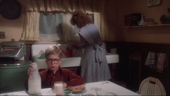 Movie still from “A Christmas Story” (1983), directed by Bob Clark – A young boy sitting at a table in front of an older woman; Medium shot, Low angle