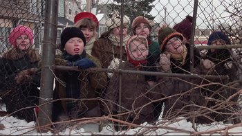 Movie still from “A Christmas Story” (1983), directed by Bob Clark – A group of children hanging out of a chain link fence; Wide shot, High angle