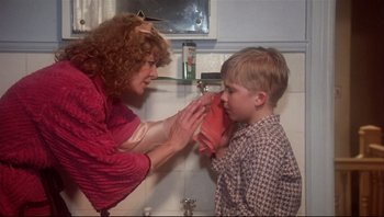 Movie still from “A Christmas Story” (1983), directed by Bob Clark – A woman is putting a bandage on a young boy's face; Close Up shot, Low angle
