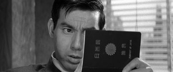 Movie still from “A Colt Is My Passport” (1967), directed by Takashi Nomura – A black and white photo of a man looking into a mirror; Close Up shot, Over the shoulder angle