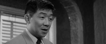 Movie still from “A Colt Is My Passport” (1967), directed by Takashi Nomura – An older asian man wearing a suit and tie; Close Up shot, Low angle