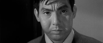Movie still from “A Colt Is My Passport” (1967), directed by Takashi Nomura – Black and white photograph of a man in a suit; Close Up shot, Over the shoulder angle
